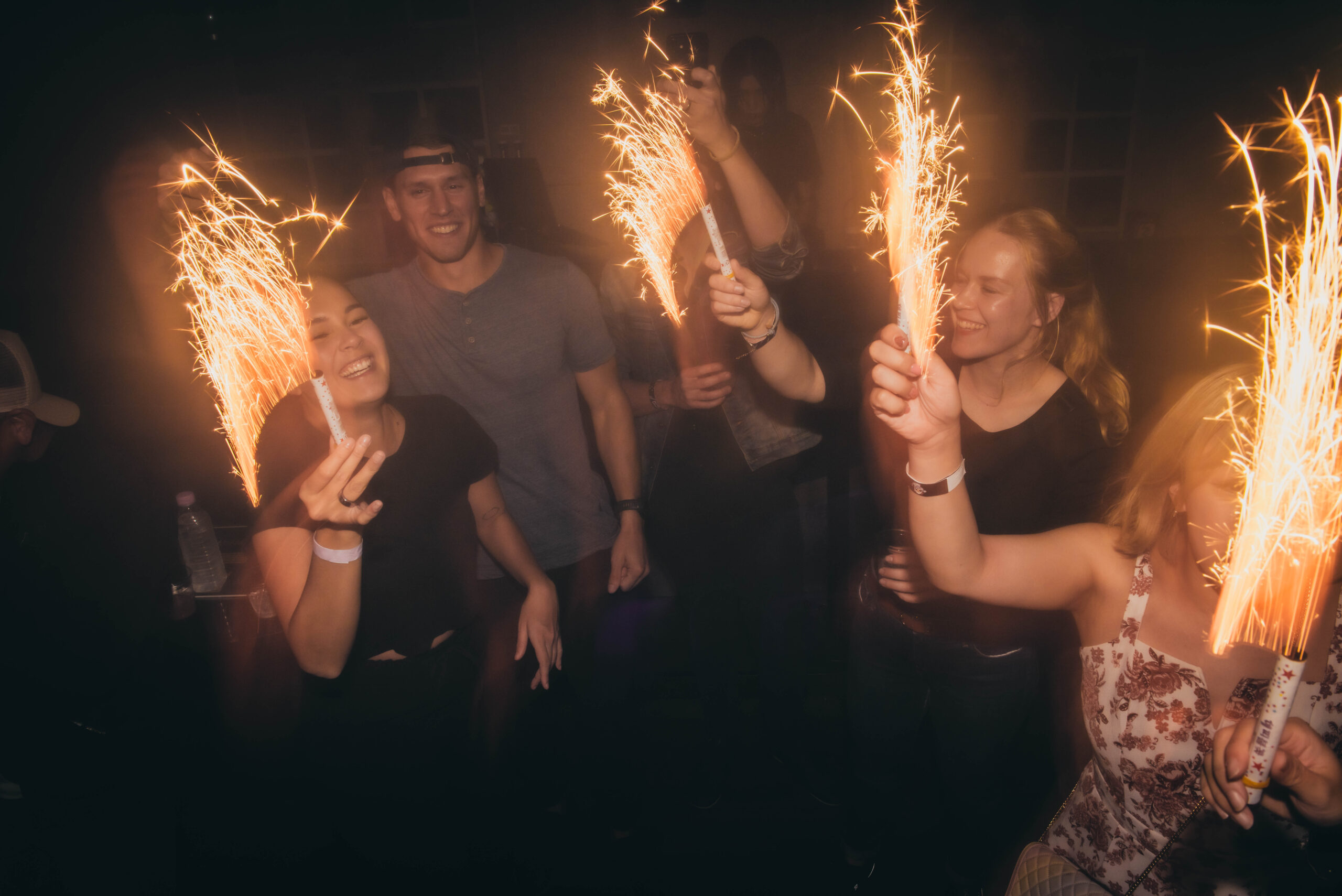 Group of people dancing with sparklers in a lively Itaewon nightclub, surrounded by vibrant lights and an energetic atmosphere.
