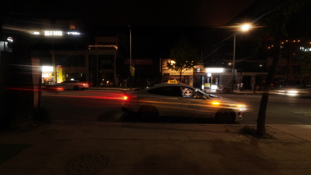 Bam driving a Seoul taxi at night, with light trails from passing traffic