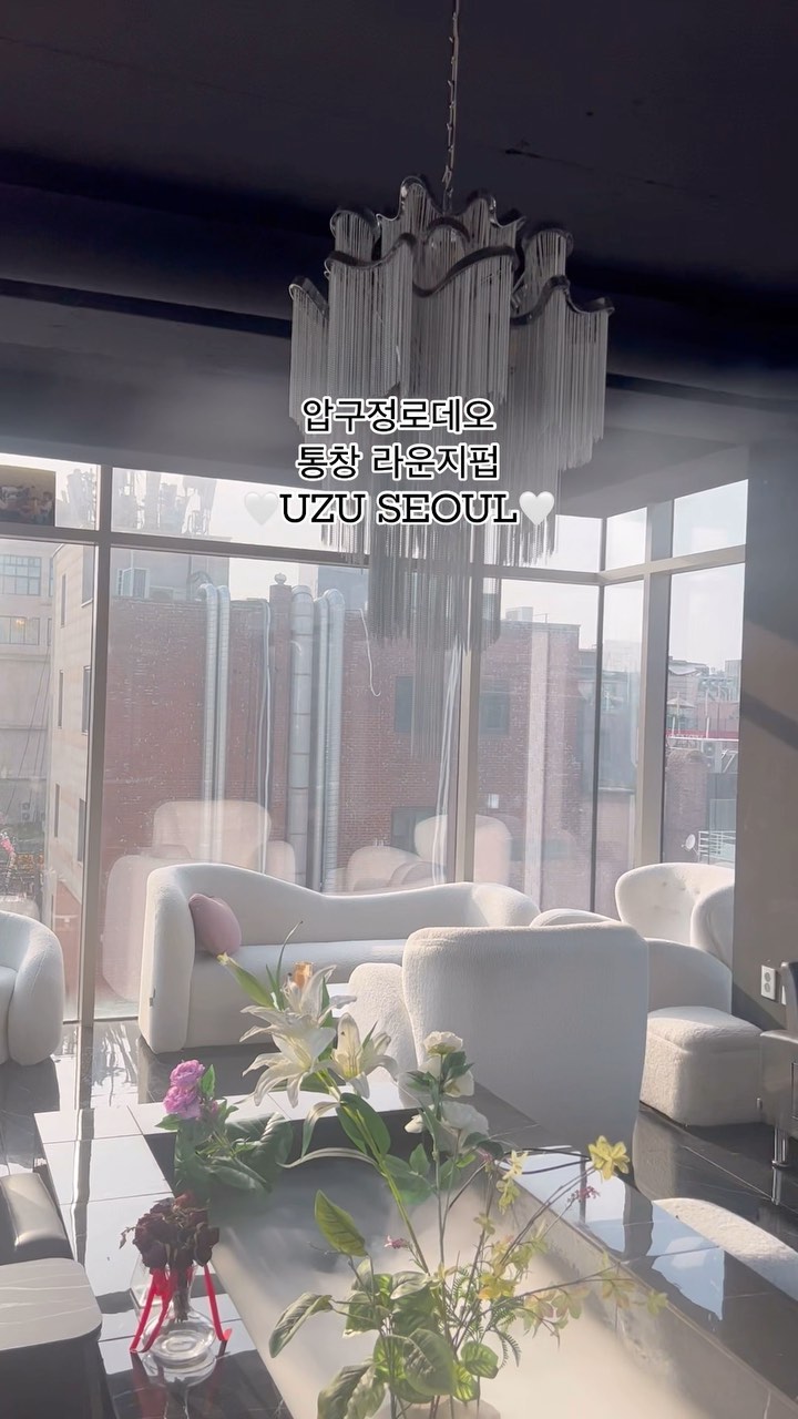 White lounge seating beneath the chandelier at UZU Apgujeong