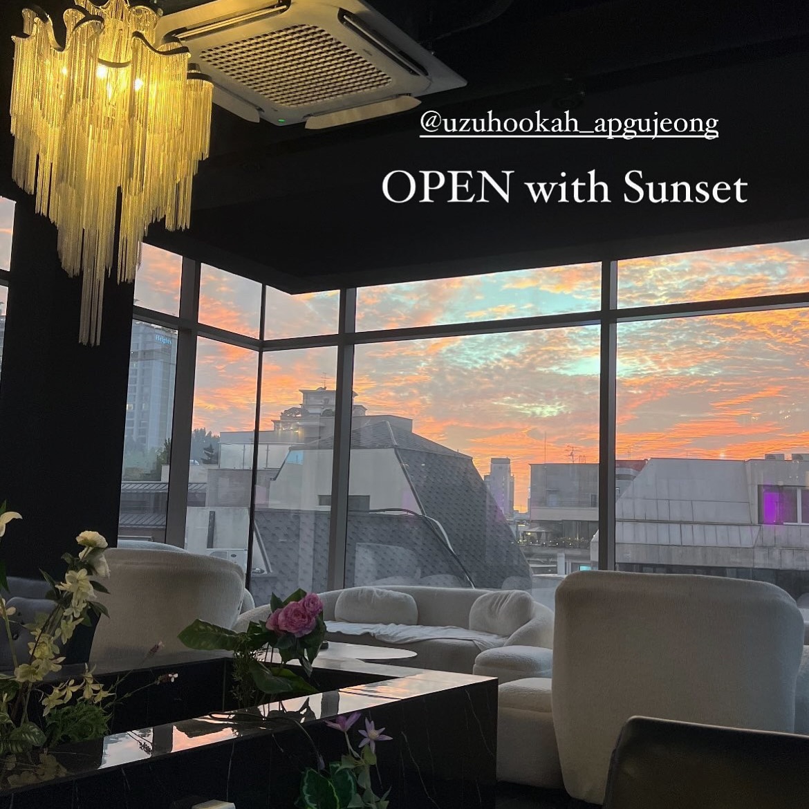 White lounge seating and large windows overlooking sunset at UZU Apgujeong