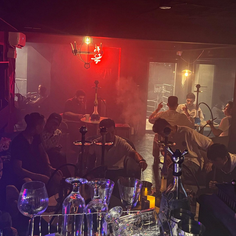 Guests seated around tables in the red-lit lounge at UZU Hongdae