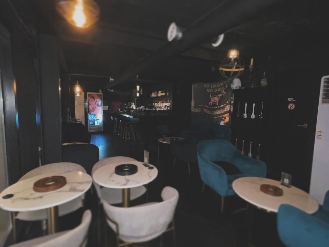 Round tables, lounge chairs and the bar inside UZU Hongdae