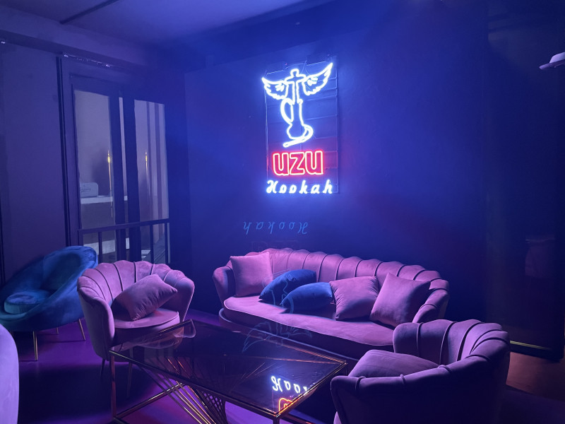Pink lounge chairs and sofa beneath the neon UZU sign at UZU Itaewon